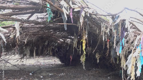 Tidal ornaments in quotes on bushes on the contaminated seashore. Multi-colored plastic pollution of the World Ocean. South China Sea, Borneo Island