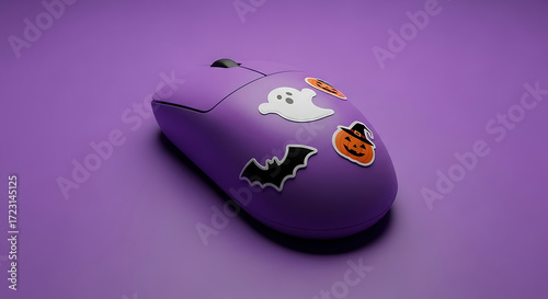 A purple computer mouse decorated with halloween themed stickers on a purple background surface view
