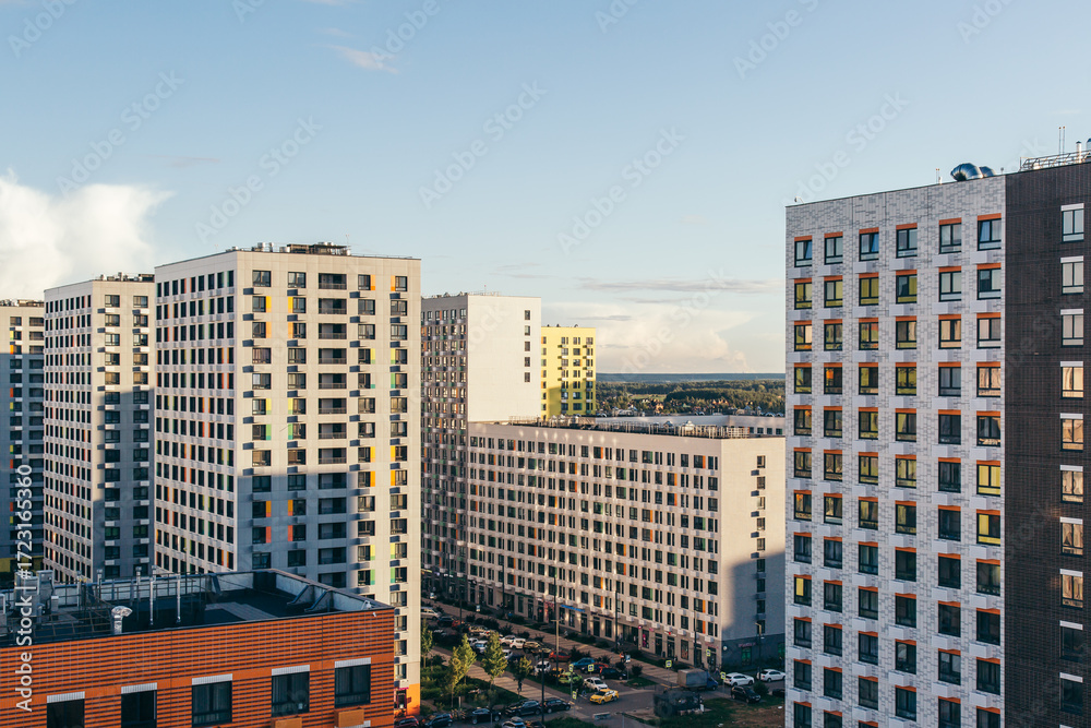 Naklejka premium Modern residential complex with tall apartment buildings and colorful facades under clear evening sky, concept of urban lifestyle, real estate rent and property investment