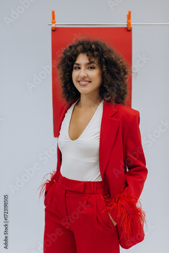 Young woman with curly hair wearing modern red suit