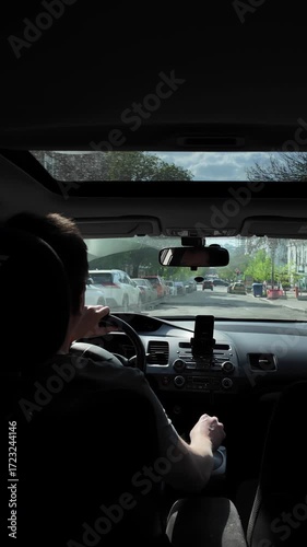 Navigating city traffic from a car interior back seat view. Vertical Video