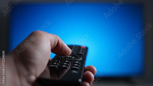 Close-up of a hand pressing a button on a TV remote control