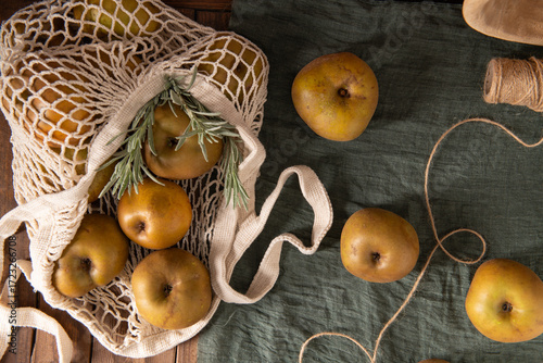 A flat lay of Reinette apples in a string bag, with a sprig of rosemary and natural twine.
