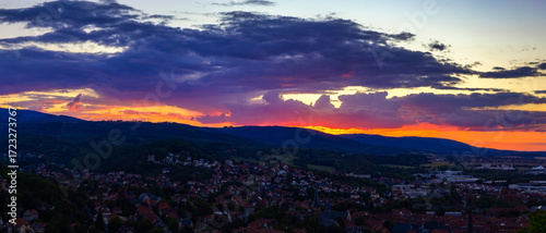 Breathtaking Panoramic Sunset Paints A Vivid Palette Of Red And Purple Across The Sky Over A Town And Forested Hills
