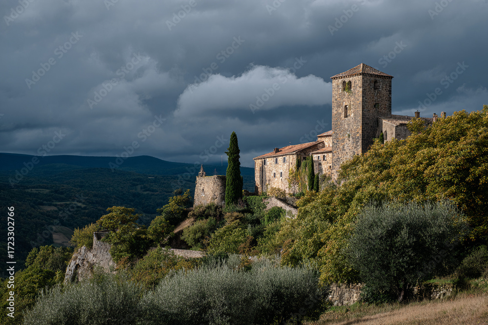 Fototapeta premium Old stone castle on a hill, dramatic clouds in the sky, side view, historical landmark