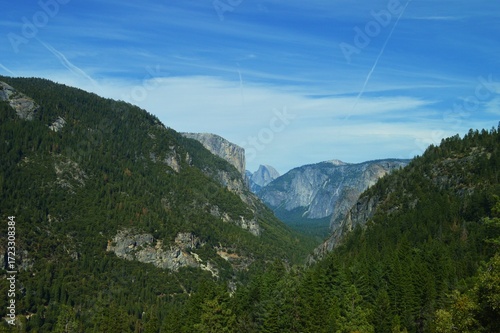 Scenic view of El Capitan and Half Dome in Yosemite National Park, California, with forested mountains under a clear blue sky