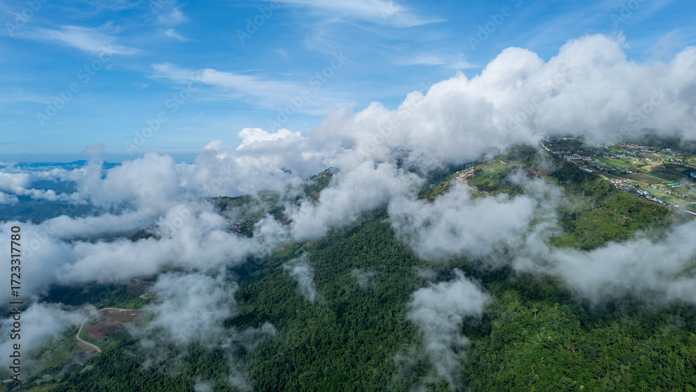 Obraz premium Aerial of Village in rain cloud cover tropical green mountain. Rainy season. Misty cover green forest. beautiful green village