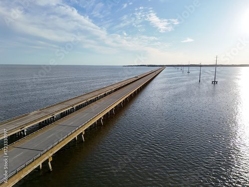Wallpaper Mural Aerial view of a straight Wright Memorial bridge crossing a tranquil sea between Kill Devil Hills and Point Harbor toward the distant horizon. The sun glints off the water, creating a serene scene. Torontodigital.ca