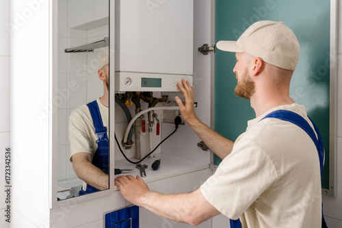 Repairman maintaining gas boiler in modern bathroom for efficient heating