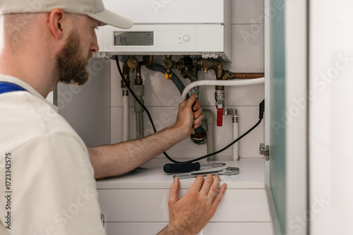 Fotografia Repairman checking gas boiler for maintenance in residential bathroom setting
