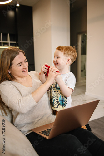 Kid make noise and disturb woman working talking on phone. Mom work on laptop from home with child. Homeschooling and freelance job. Quarantine and closed nursery school. Distance learning through war