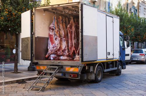 Meat factory with pork and beef hanging on hooks in refrigerated delivery truck