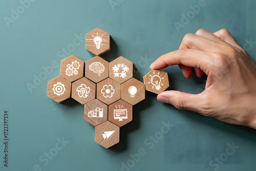 Hand placing a hexagonal block with a gear icon into a larger structure of connected blocks