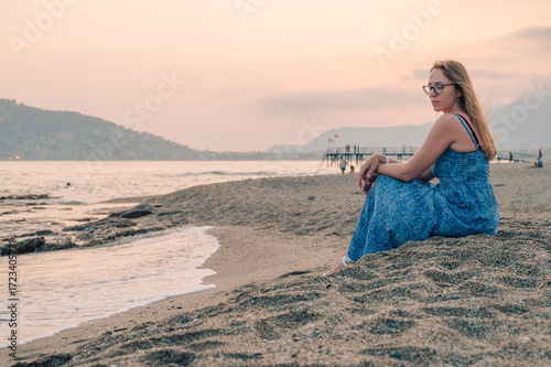 Woman sits on the beach and...