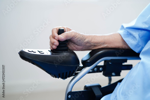 Asian elderly disability woman patient use joystick electric wheelchair in hospital.