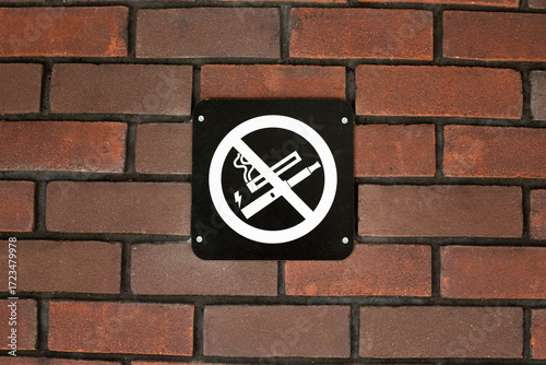 No smoking and no vaping sign displayed on brick wall, highlighting prohibition of both traditional cigarettes and electronic cigarettes and vapes in public spaces, emphasizing health concerns
