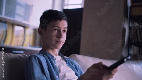 Evening Chill: Young Boy Browsing TV Channels from the Comfort of the Couch