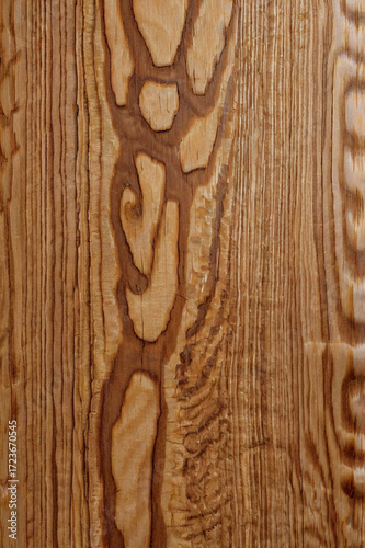 This image shows a close-up view of a wooden surface with a smooth, polished finish. The wood grain is visible, running vertically with a light tan or beige color and subtle texture.