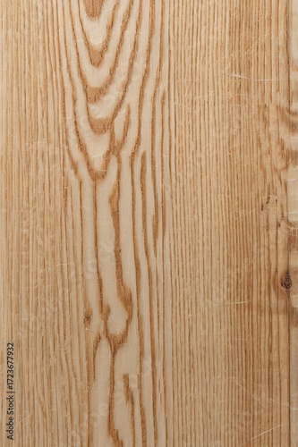This image shows a natural wooden surface with a distinct and bold grain pattern. The wood has a warm beige tone with dark brown lines forming wavy, organic shapes along the length.