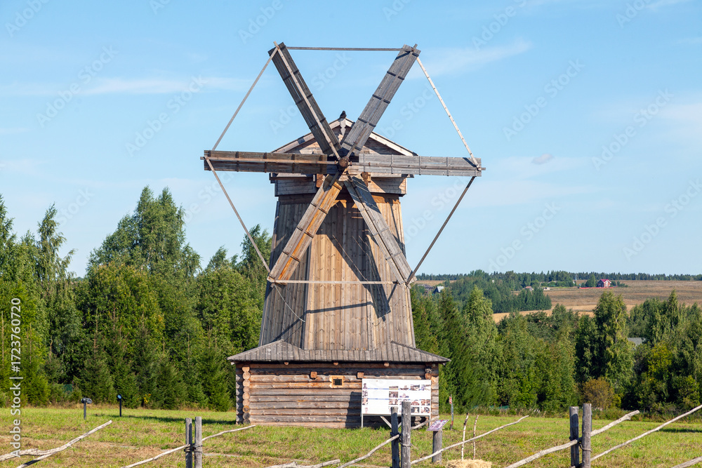Obraz premium Historic Wooden Windmill with Large Blades under Blue Sky
