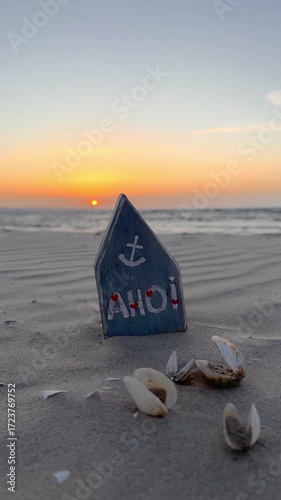 self crafted maritime house stands on a sandy beach against the tranquil ocean backdrop, warm glow of the sun casts long shadows