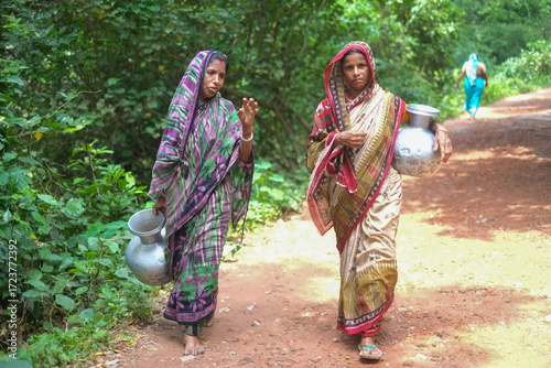 Women gossiping and carrying water pitcher on a village track