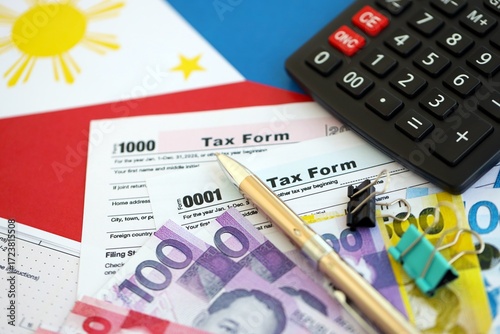 Philippines peso money bills and calculator with tax form on flag close up. Taxation and accounting concept