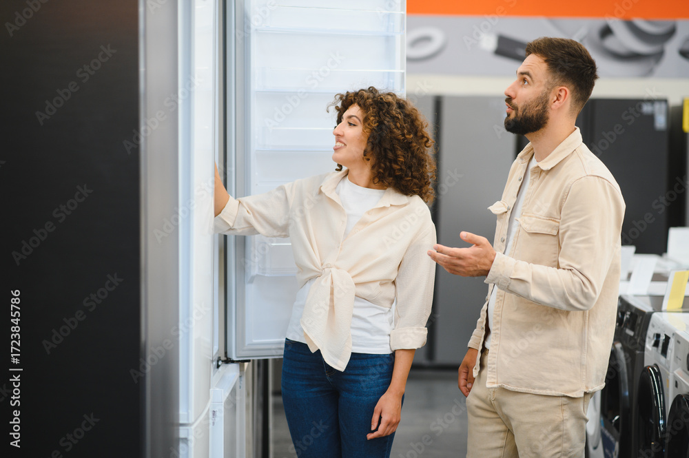 Naklejka premium Couple exploring refrigerators in electronics store
