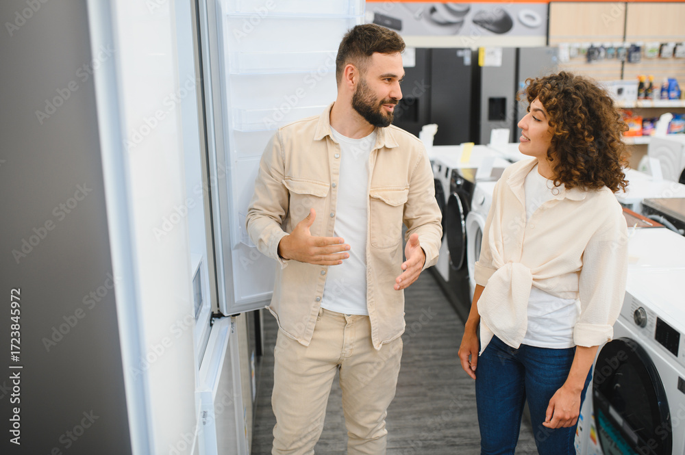Fototapeta premium Couple choosing refrigerator in home appliance store