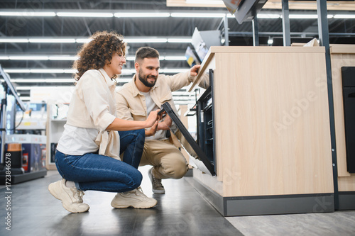 Couple choosing new oven in electronics store