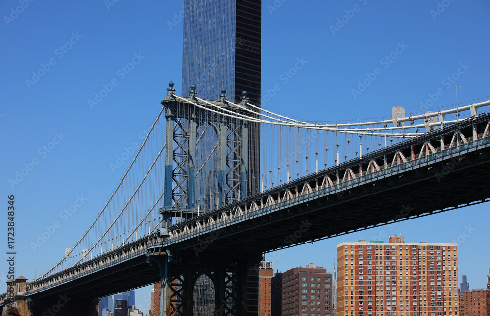 Naklejka premium manhattan bridge viewed from under and behind modern skyscraper in new york usa
