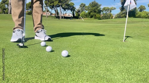 A man is playing golf and has just hit a ball. The ball is in the air and is heading towards the hole
