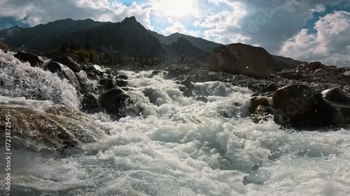 The sun illuminates a bubbling mountain stream among rocks