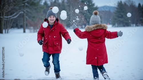 Children throwing snowballs in park during winter in snow jackets, background