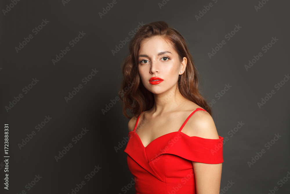 Naklejka premium Perfect brunette woman with trendy make-up and brown curly hair wavy hairstyle and red lips makeup on black background
