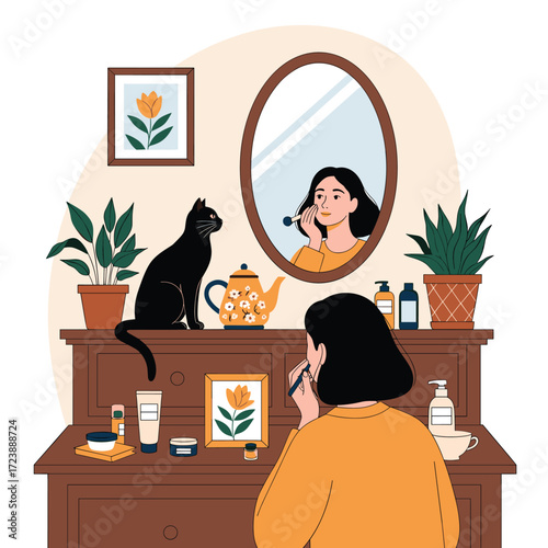 A woman applies makeup in front of a mirror with a cat nearby.