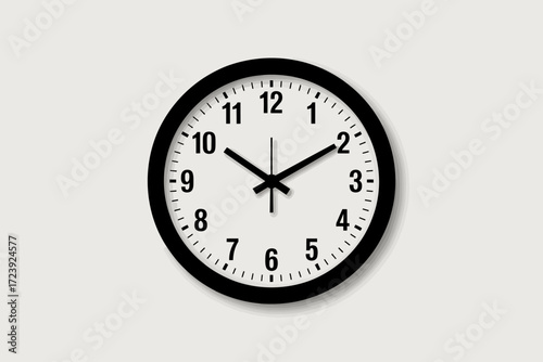Simple black and white wall clock showing the passage of time against a neutral background.