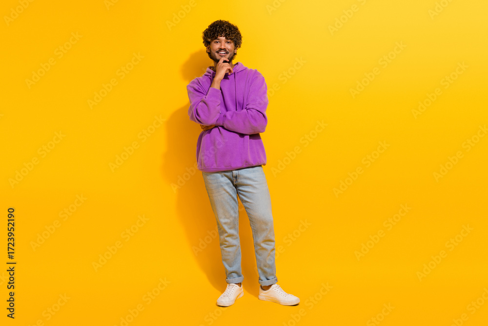 Fototapeta premium Cheerful Young man wearing a stylish hoodie smiling confidently against a bright yellow background