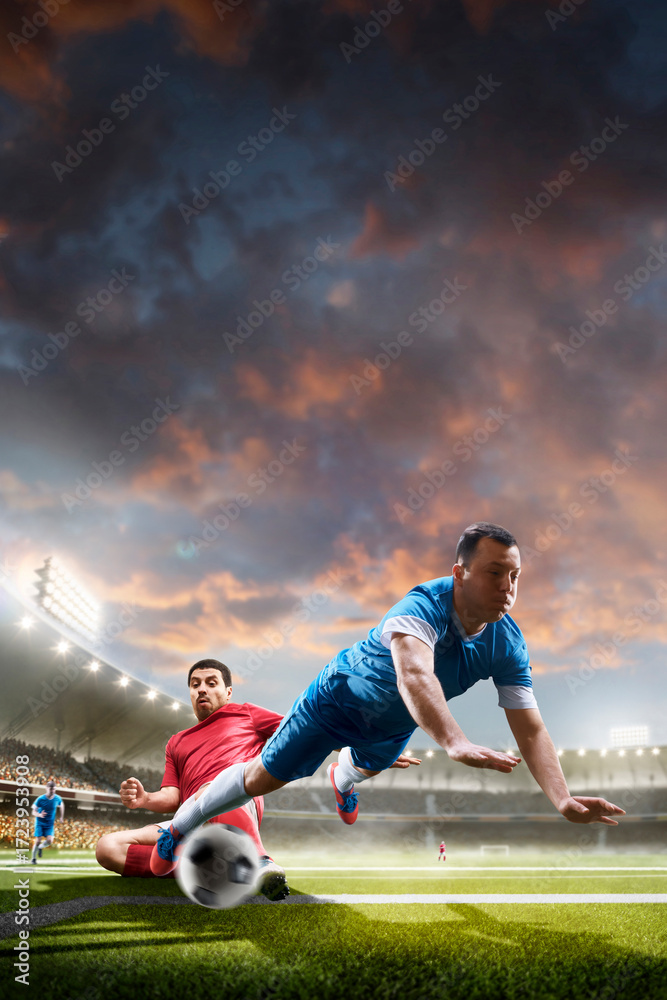 Obraz premium Sports concept. Professional soccer players in action. Tackling the ball. Soccer championship. Sunset on stadium. Soccer. Soccer arena full of fans. Vertical
