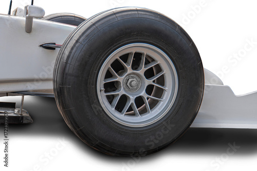 Close-up of a worn Formula 1 tire with irregular hubcap, off-center right, suspended assembly visible, outdoor daylight setting a