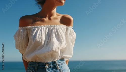 Woman in white top and blue jeans by the ocean