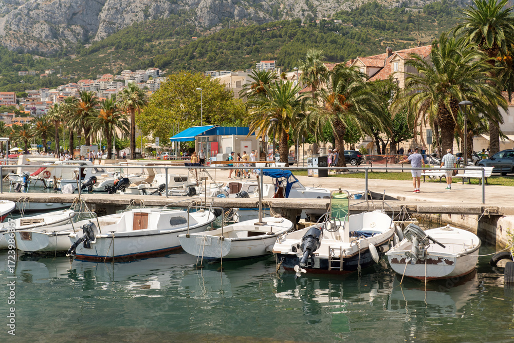 Obraz premium Small motorboats moored at the pier on the palm-lined promenade