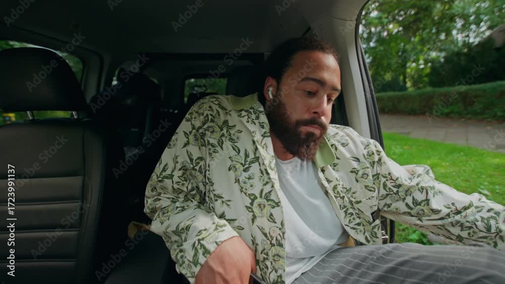 Front view of the man from the car as he gets into the driver's seat. A man in casual clothes gets into a car parked near his house.