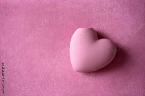 Clitoral stimulator. Heart shaped satisfyer sex toy for women. Masturbation device over pink towel background