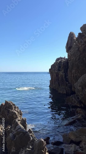 A brave young man jumps headfirst from a high cliff into the deep blue sea. A summer extreme sport and a thrilling adventure.