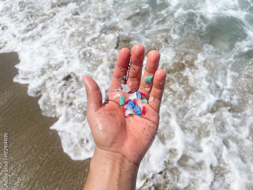 Micro plastics or Microplastics found on the beach on a person's hand on Mexico, sea sand in the background.