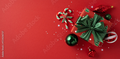 A festive Christmas gift banner with a green bow sits among decorative ornaments and candy canes on a red backdrop, capturing holiday cheer, festive mood, and seasonal celebration