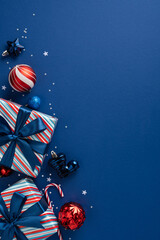 Colorful vertical Christmas gifts with striped wrap, blue ribbon bows, and shiny ornament ready for celebration. A festive scene of joy, sparkle, and holiday greeting against a rich blue background