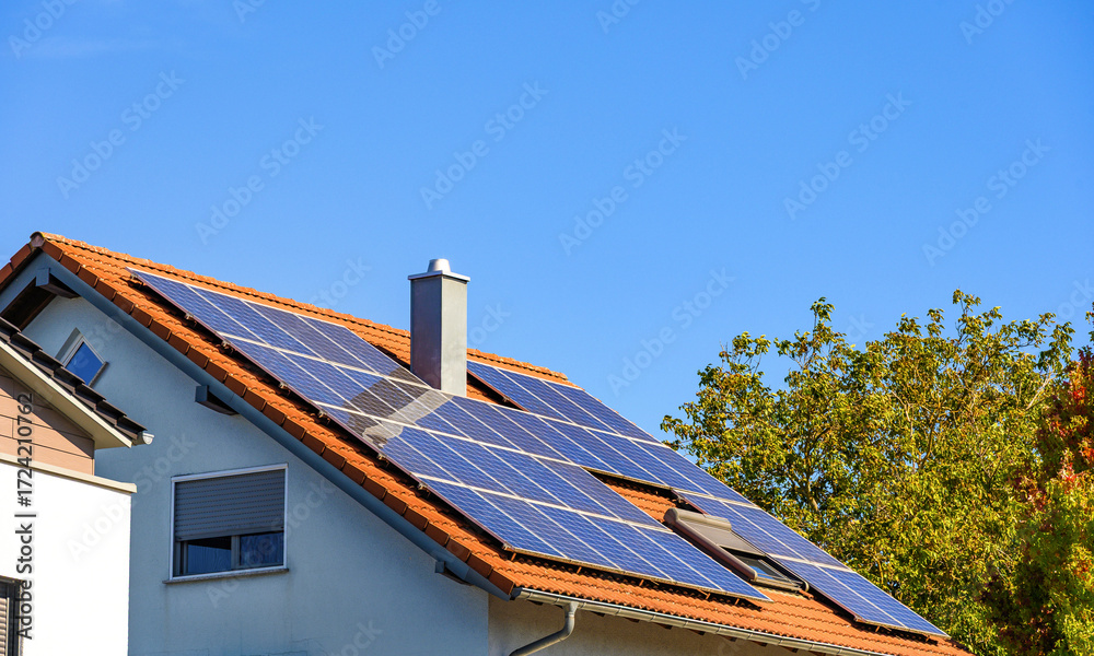 Fototapeta premium Photovoltaikanlage auf rotem Hausdach vor blauem Himmel