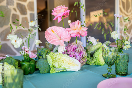 Konstfotografi A Vibrant Table Arrangement Featuring Colorful Flowers and Fresh Vegetables for